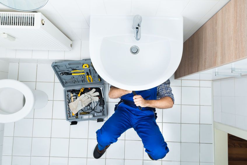 plumber repairing leaky bathroom sink